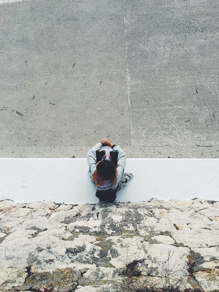 people top view of person sitting near gray rock wall during daytime person