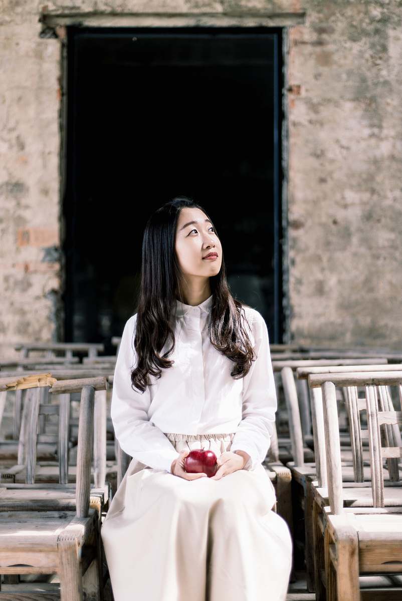 woman woman in white button-up dress shirt and white pants holding apple sitting on chair apple