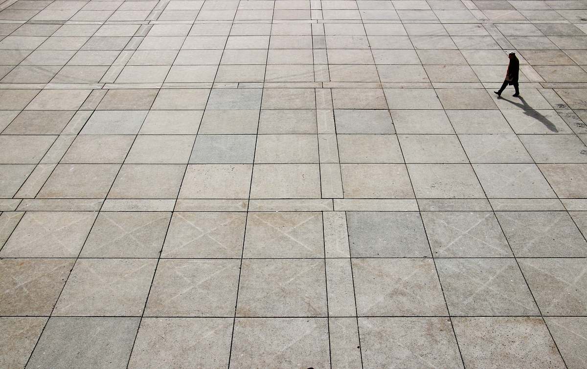 grey man walking on tiled ground at daytime nathan phillips square