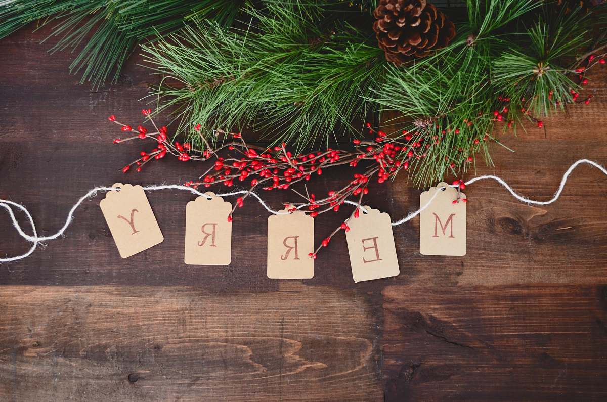 christmas MERRY text cutout on white string by wreath tree