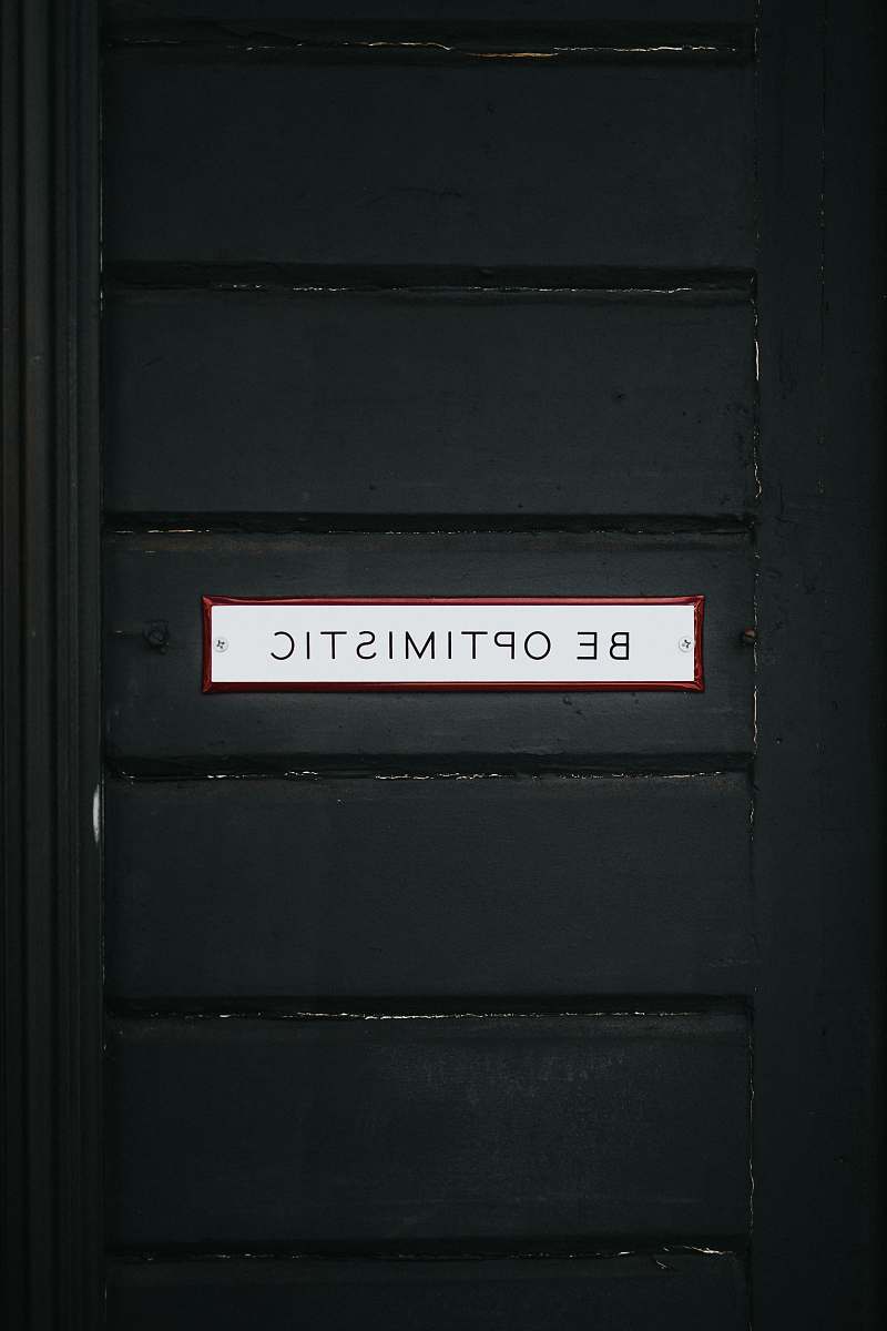 sign black wooden door with be optimistic text overlay words