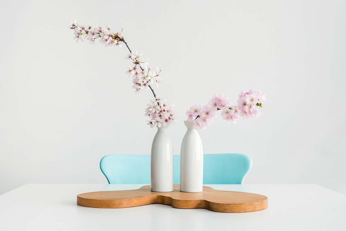 table two pink petaled flowers in white vases on brown wooden surface flower