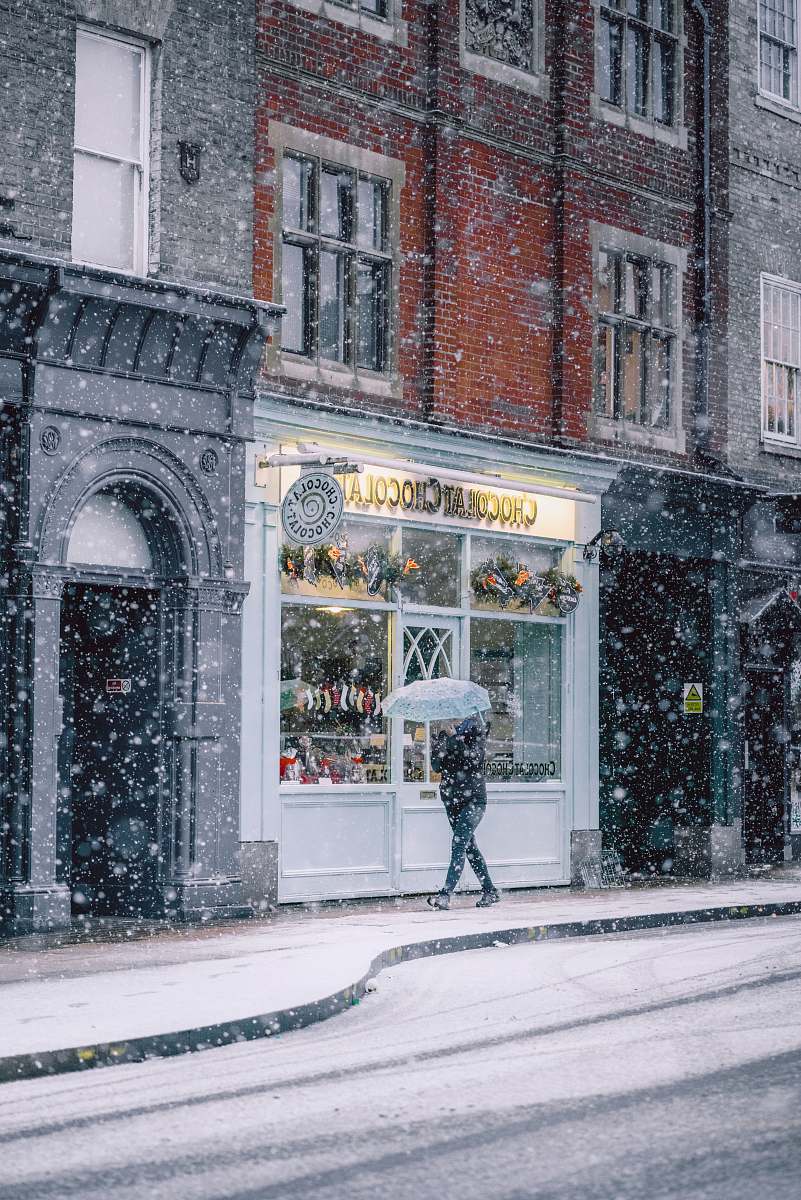 snow parson walking near cafe during winter umbrella