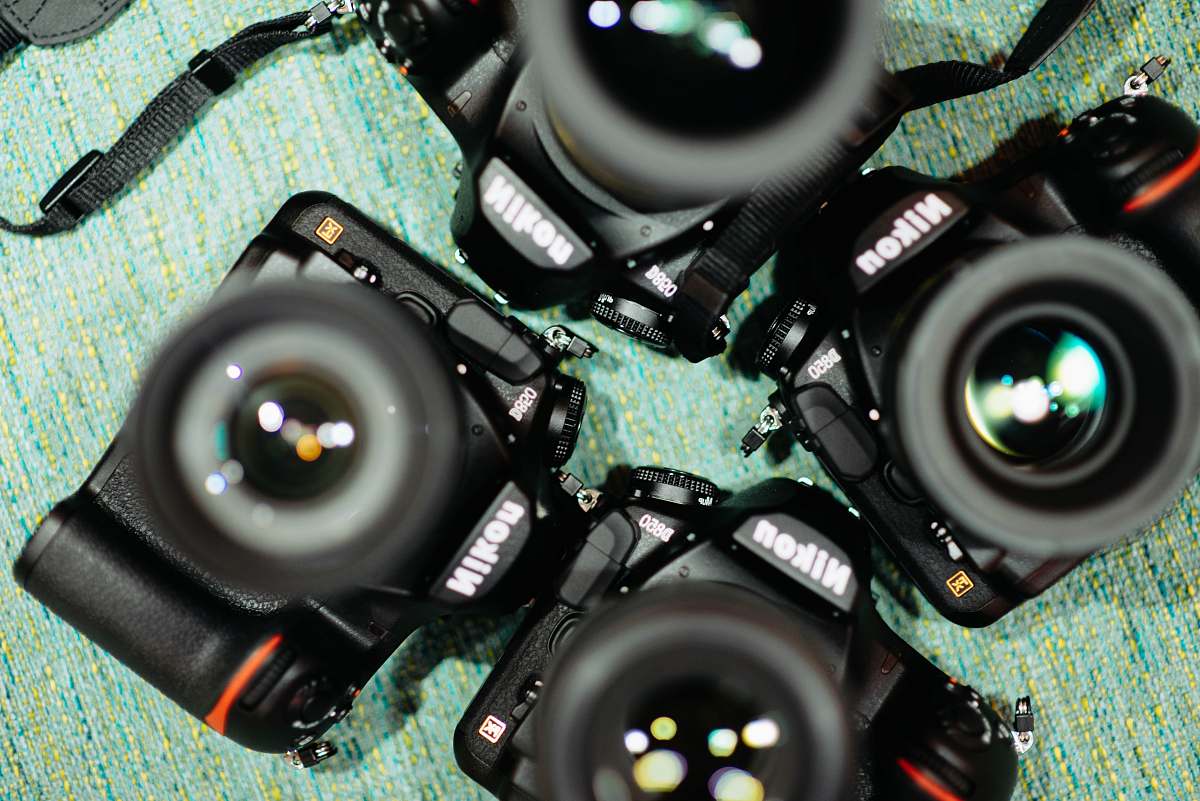 camera four black Nikon DSLR cameras on green textile nikon