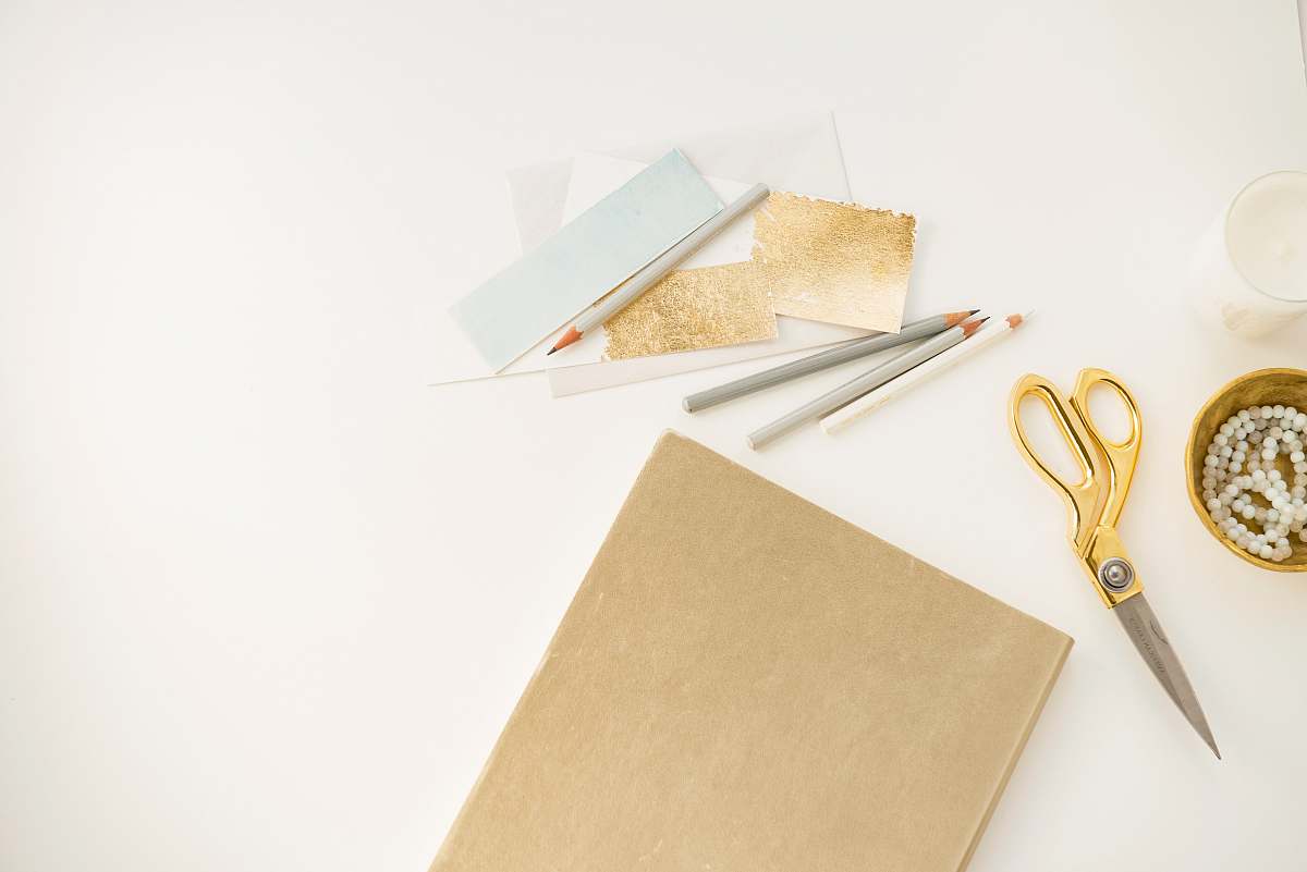 gold yellow handled scissors beside brown paper desk