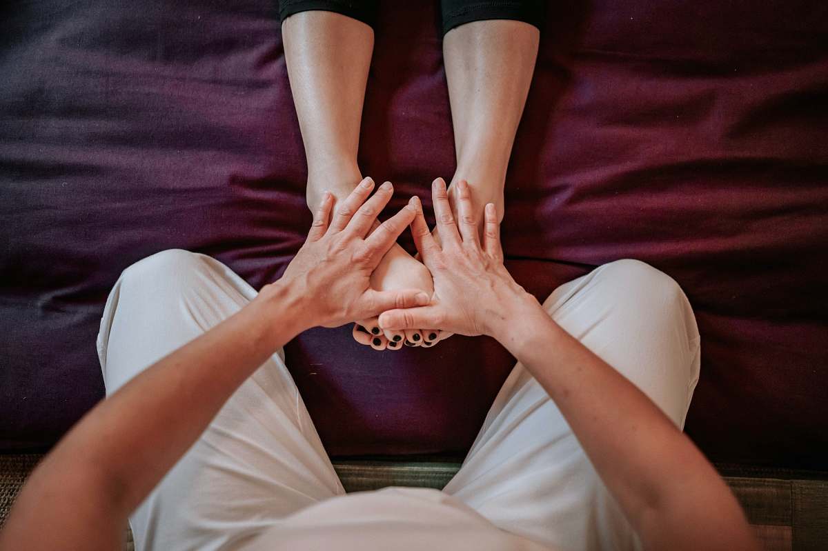  person in black pants lying on white bed 