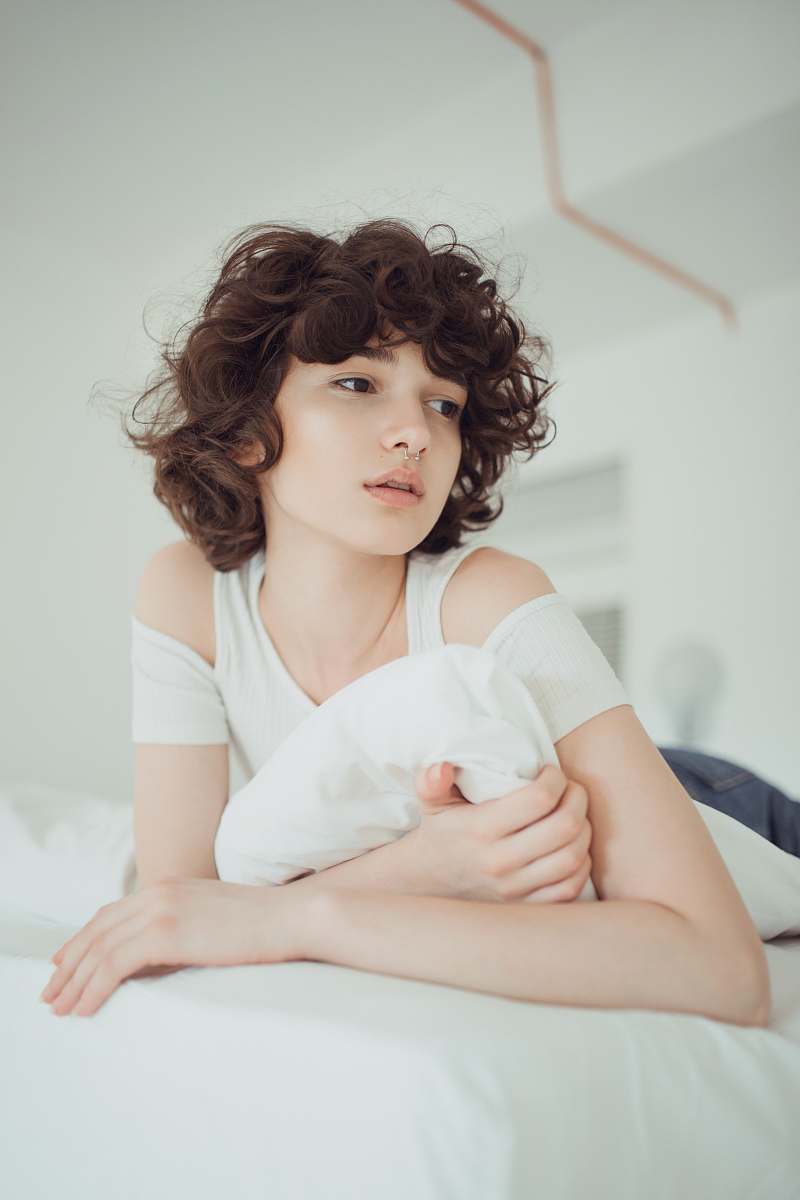  woman in white shirt lying on bed 