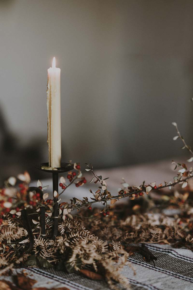 fire lighted candle on candlestick on top of table grey