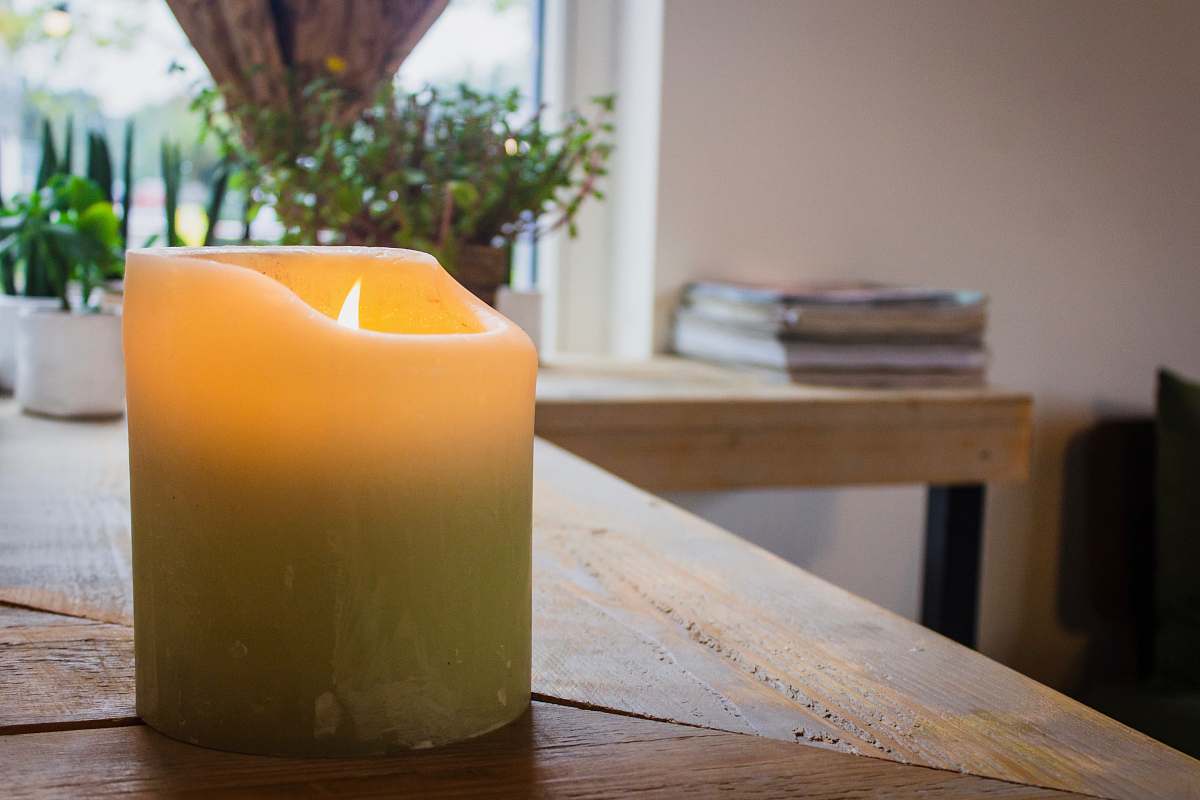 wood lighted white pillar candle on table hardwood