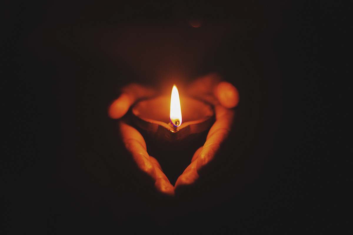 fire person holding lighted oil lamp flame