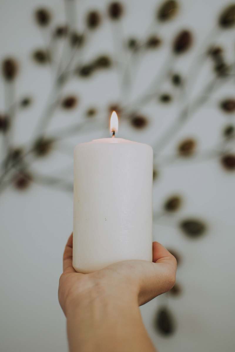human selective focus photography of lighted pillar candle person