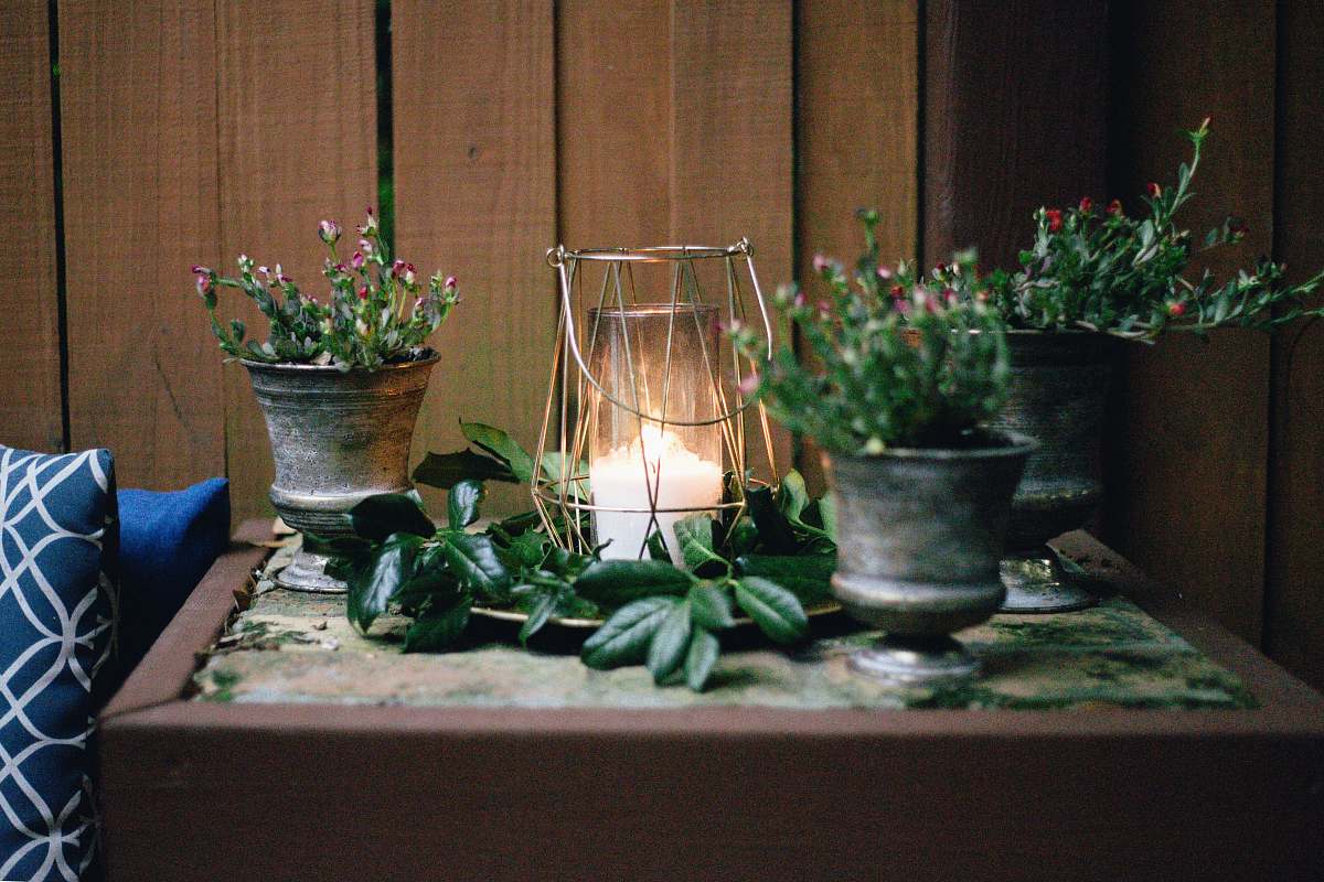 pottery lighted candle on table beside pots flora