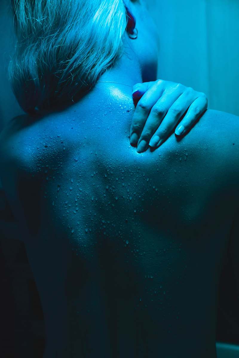 back woman covering her face with her hands blue