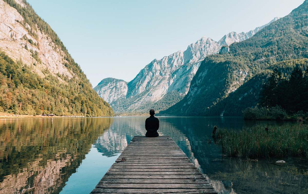 travel man sitting on gray dock meditation