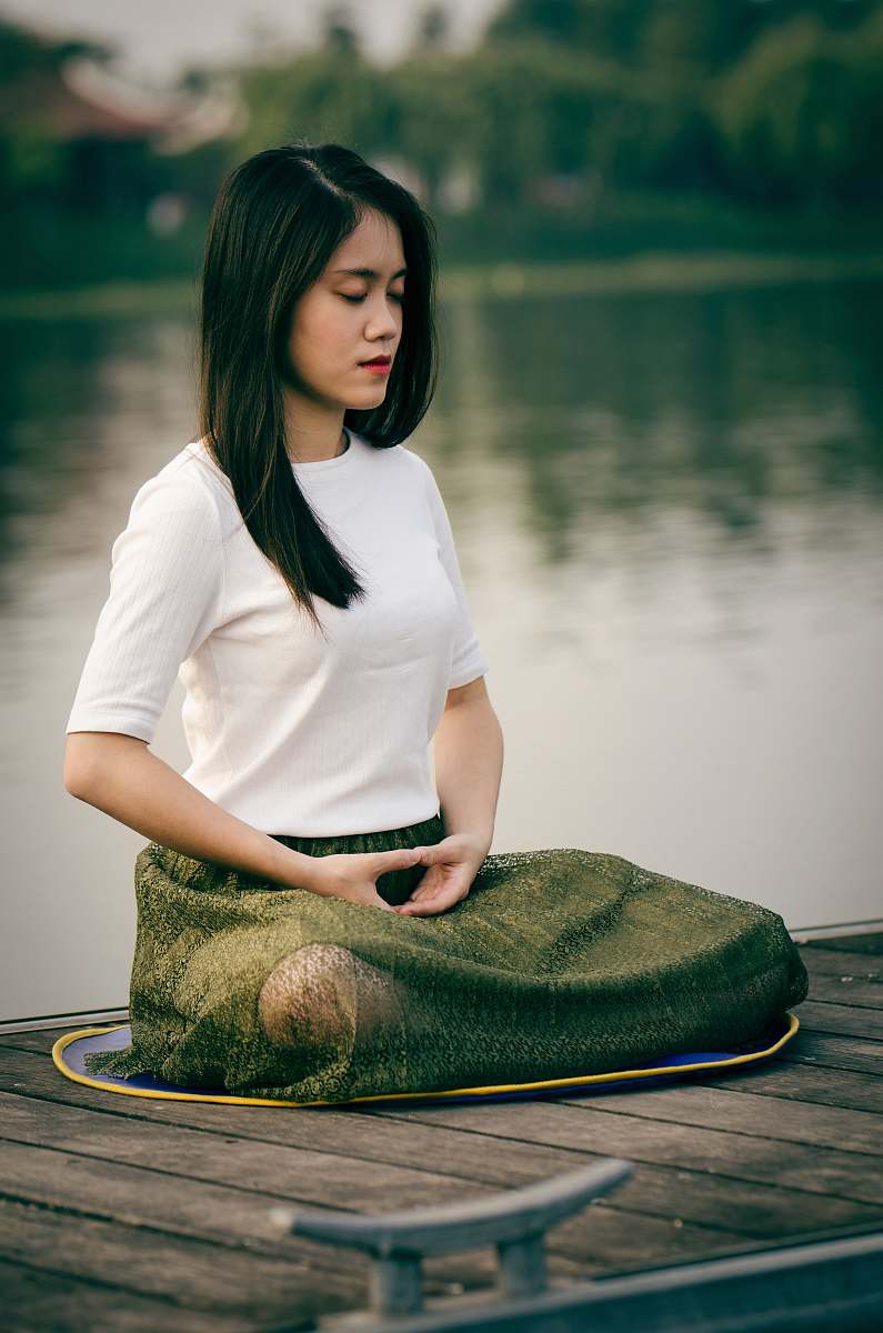 people woman meditating on wooden dock during daytime female