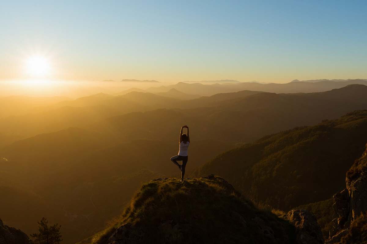 nature woman stretching on mountain top during sunrise sunset
