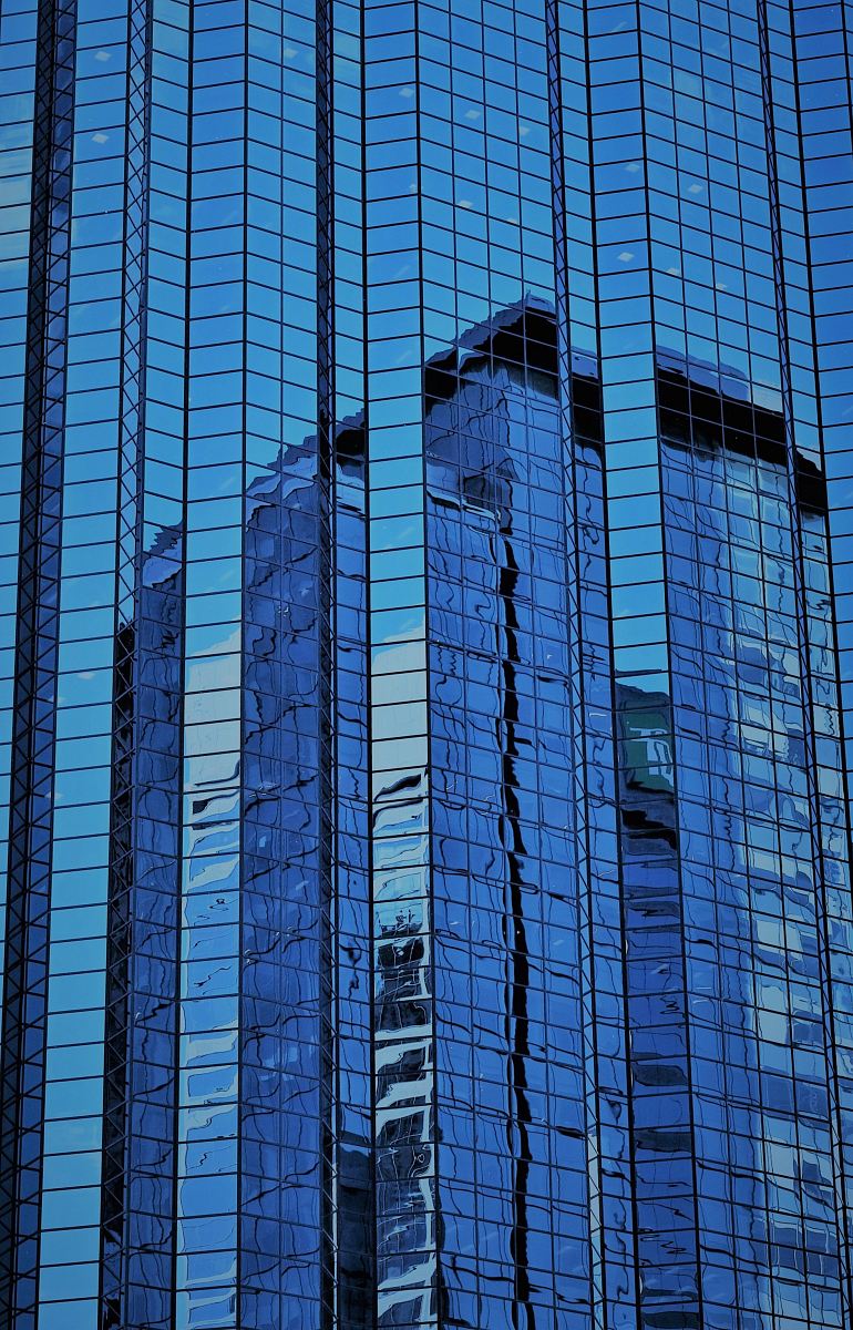 a building reflected in the glass windows of another building