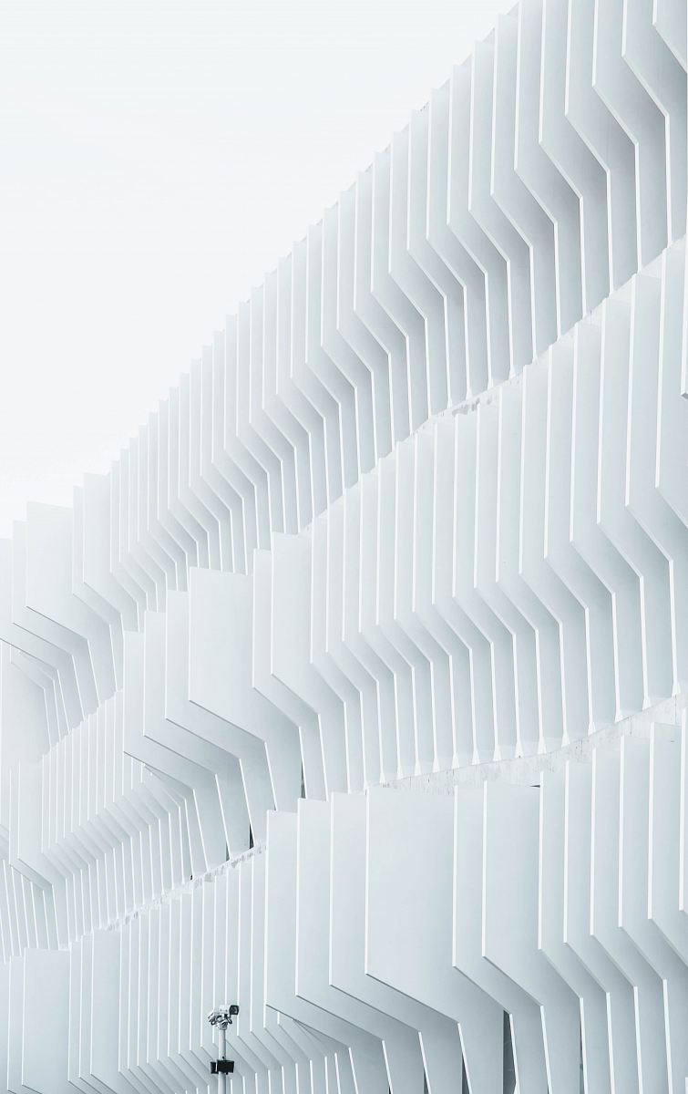 A security camera near parallel white ribs in a building facade in Madrid
