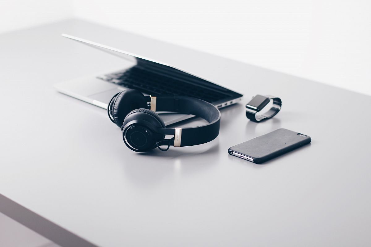 black cordless headphones beside closed black laptop computer and smartphone
