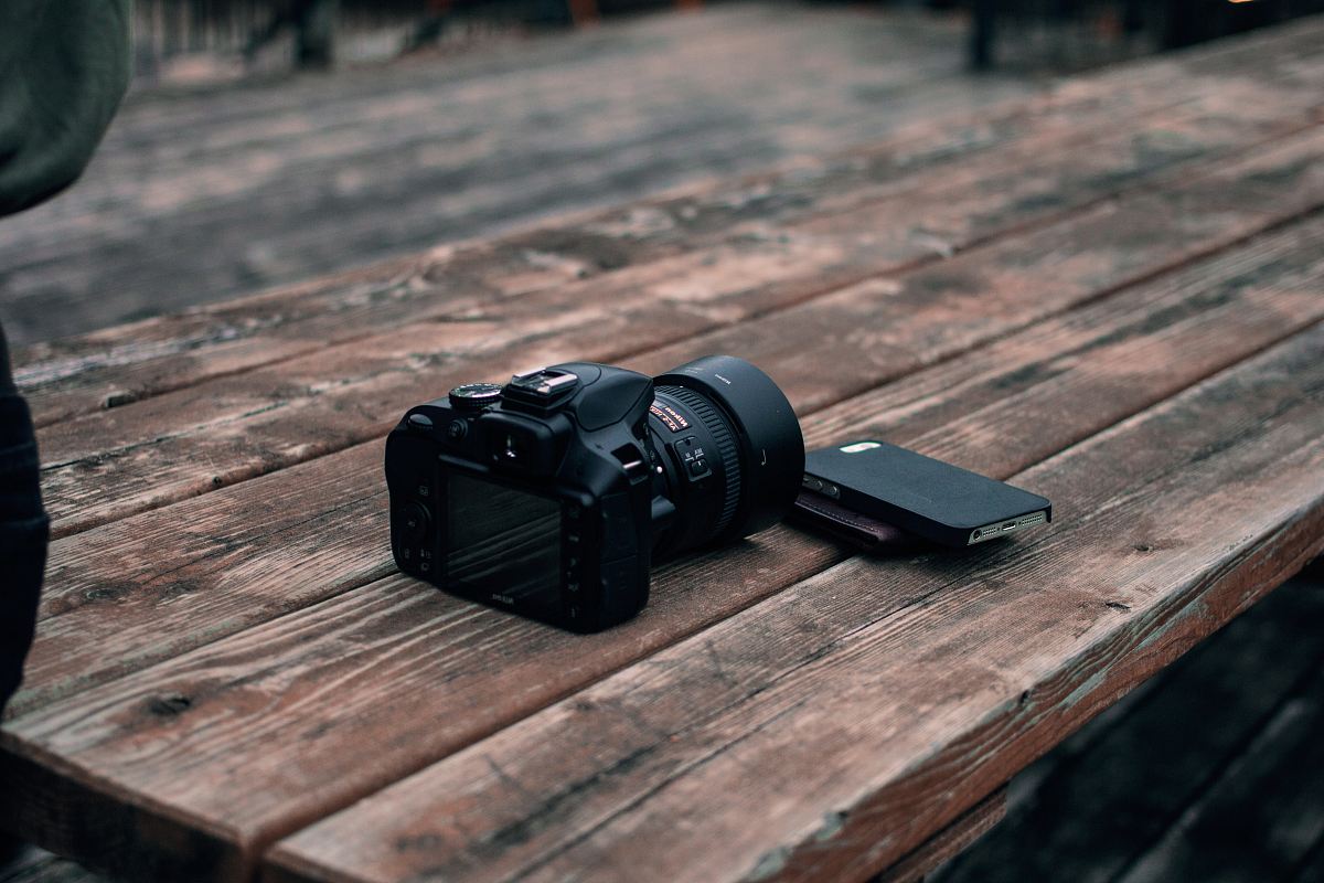 black DSLR camera on top of brown wooden table