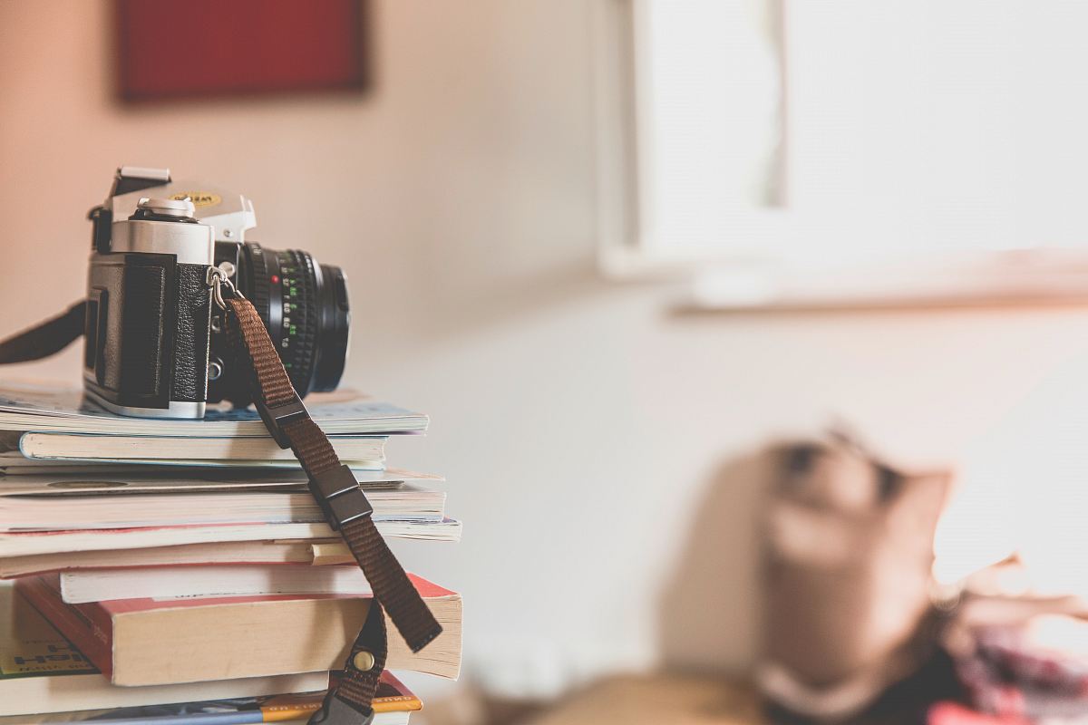 black film camera on top of piled books inside well lighted room