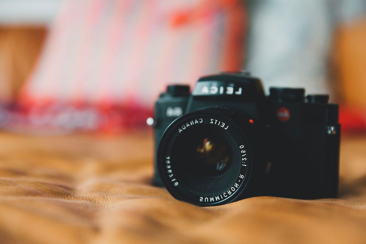 black Leica DSLR camera on brown surface