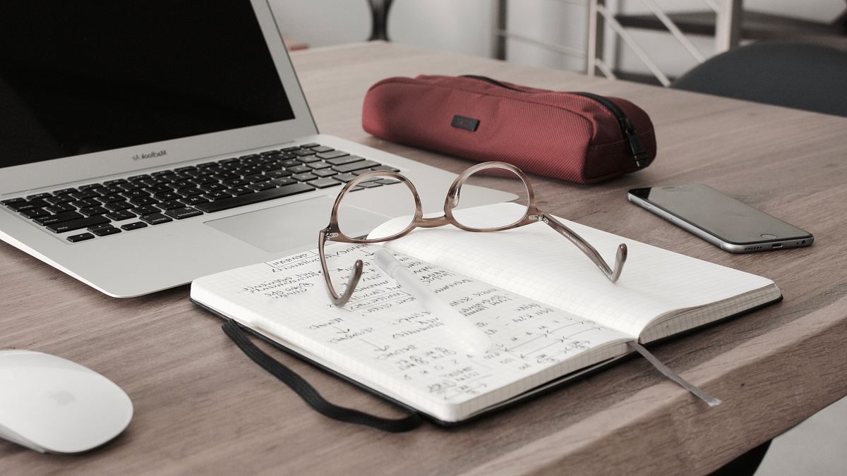 eyeglasses on book beside laptop