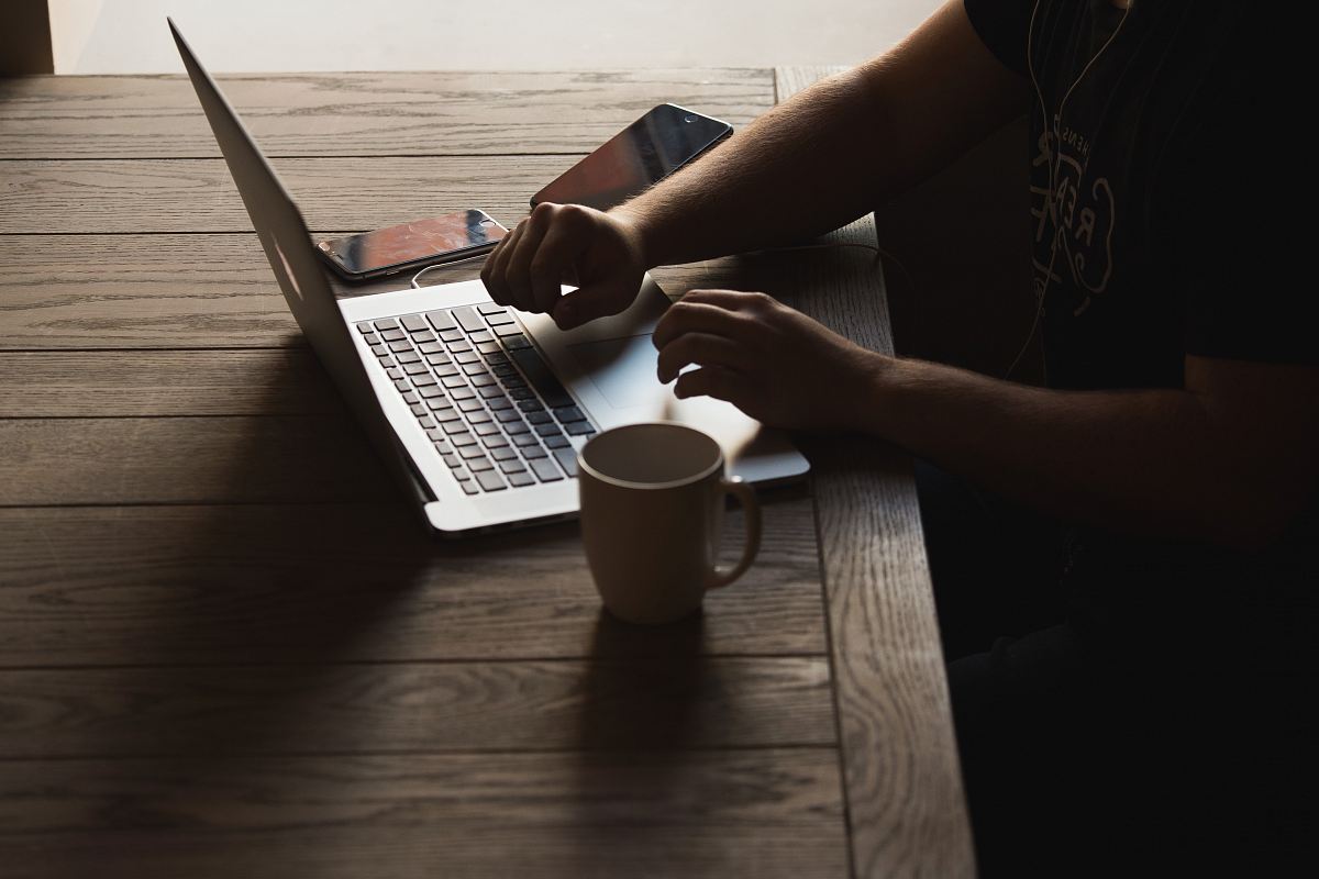 gray laptop computer on brown wooden table beside person sitting on chair