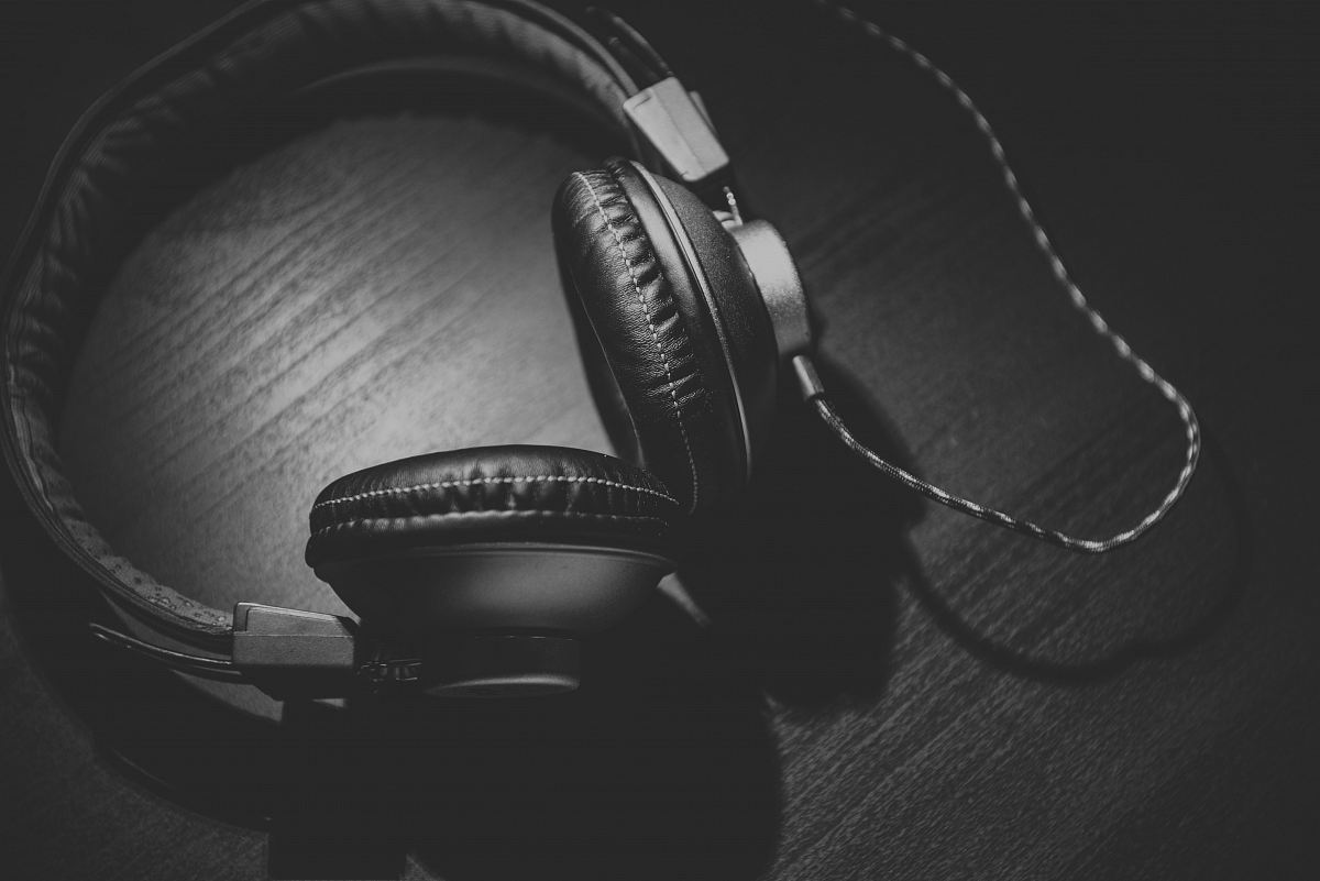 grayscale photo of corded headphones on table