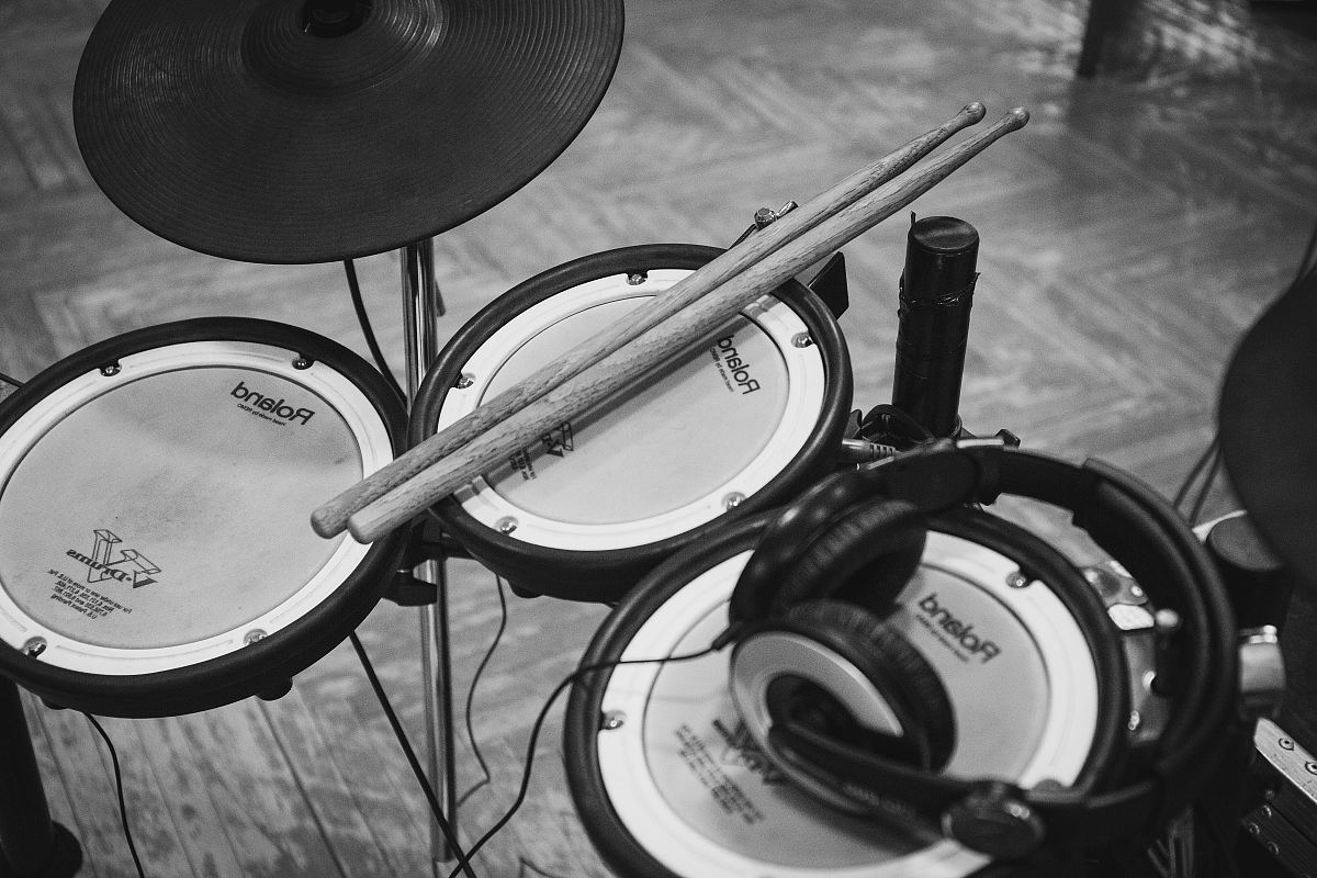 grayscale photo of drumsticks on electric drum kit