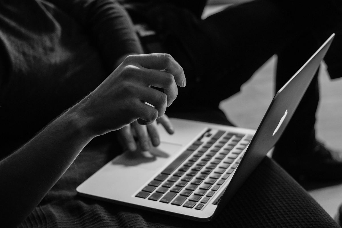grayscale photo of person using MacBook