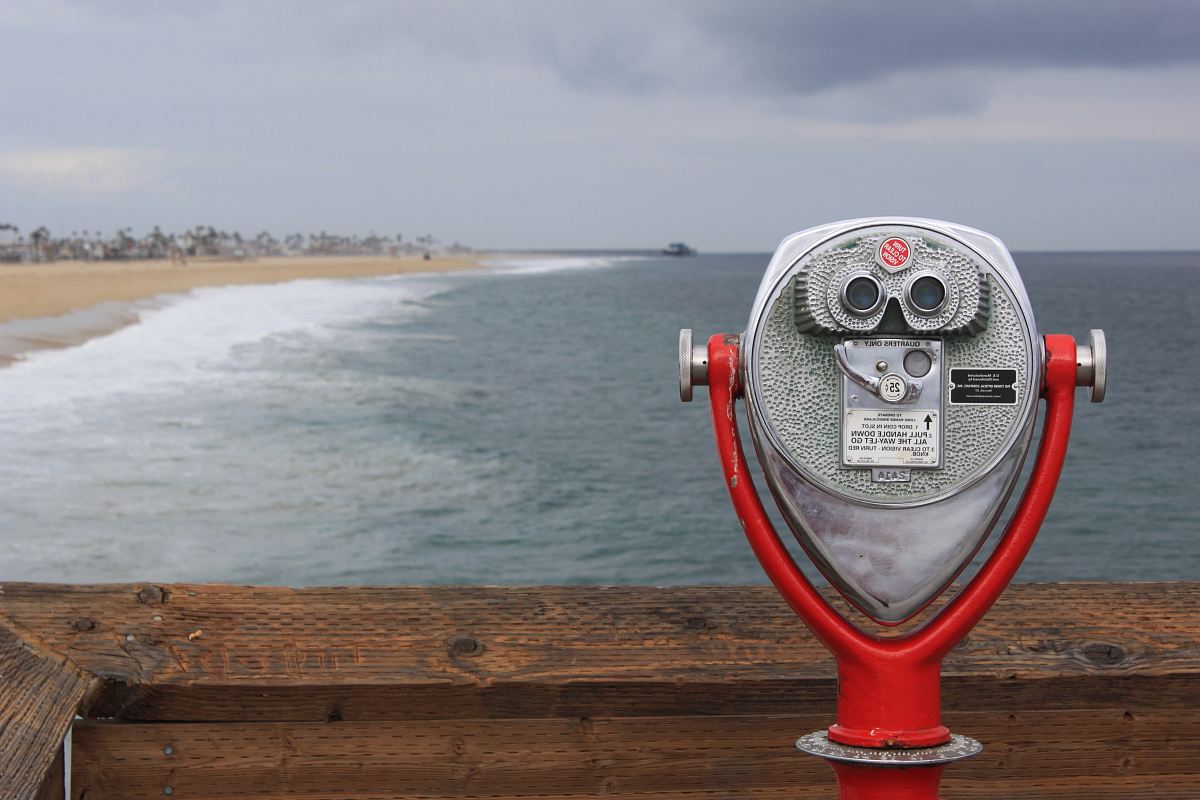 grey and red coin operated binoculars in front of seawaves under nimbus clouds during daytime