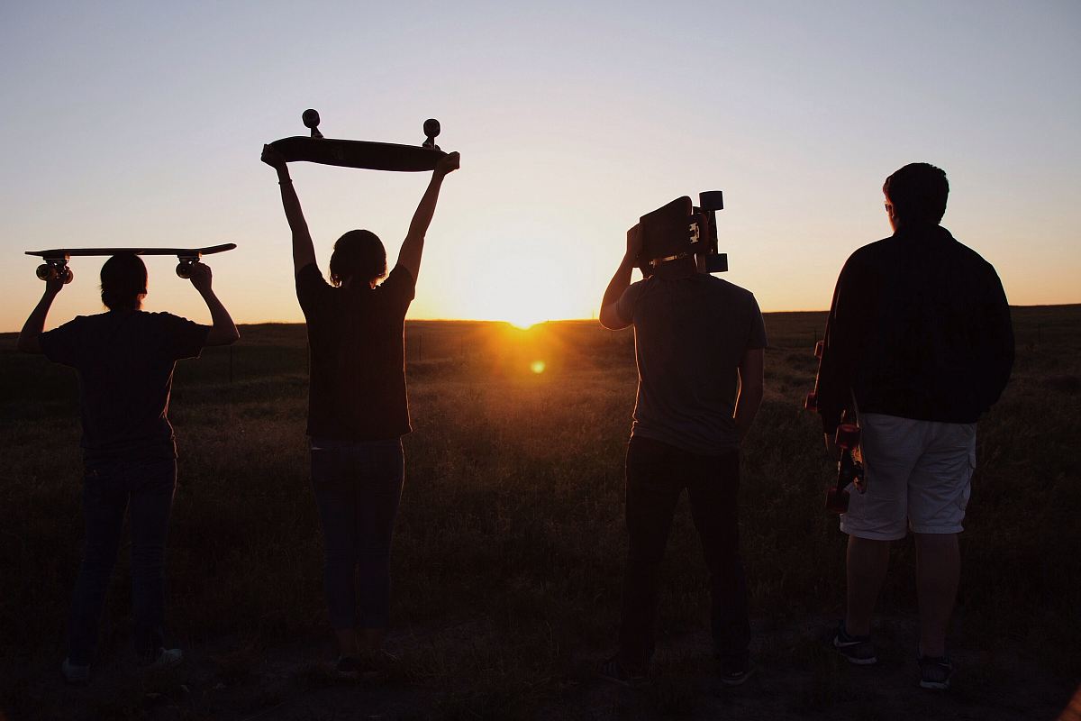 group of people holding skateboards under sunset