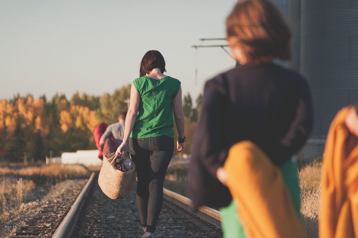 group of people walking on train tracks during sunrise