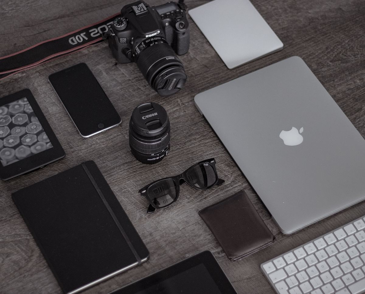iPad near sunglasses, wallet, and DSLR camera