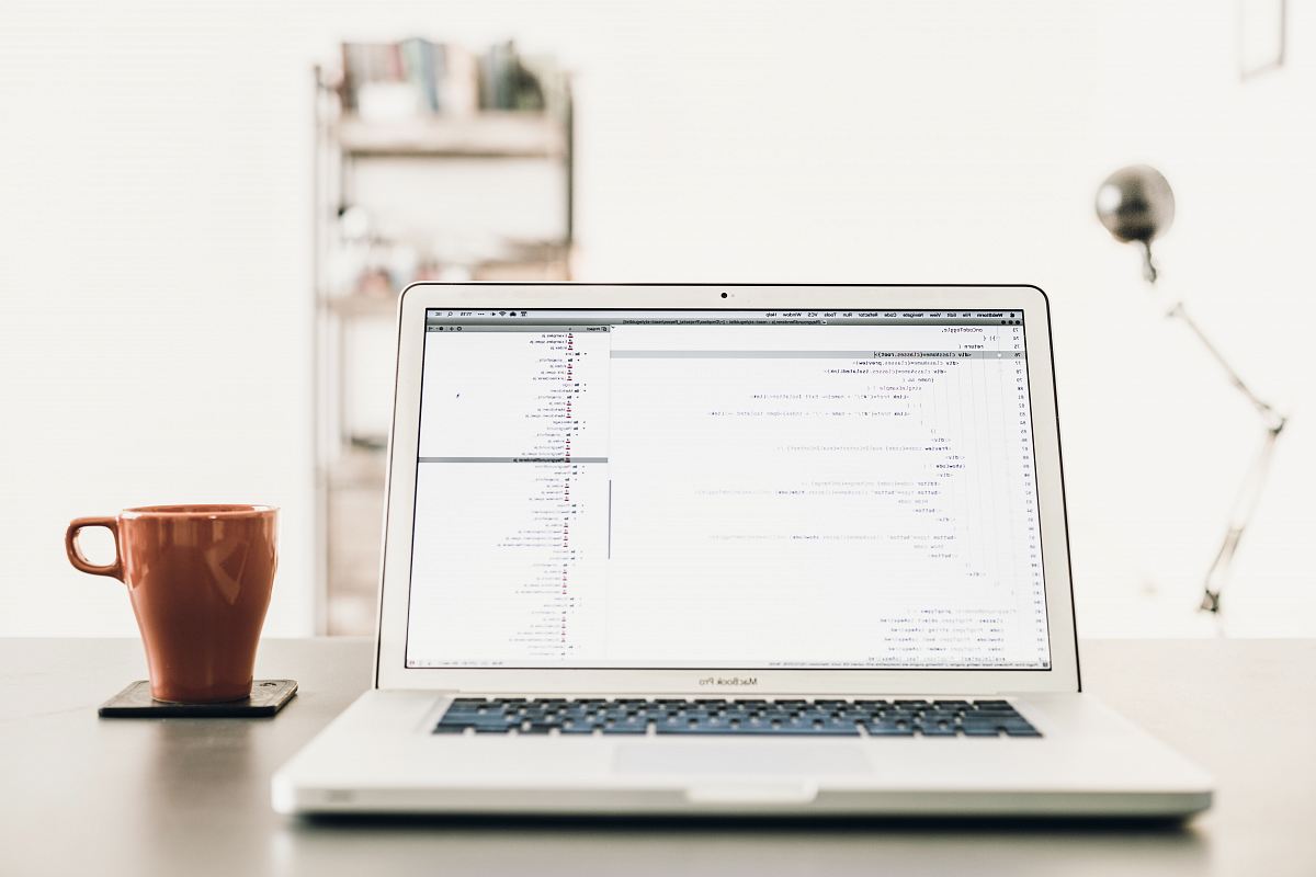 MacBOok Pro beside brown mug