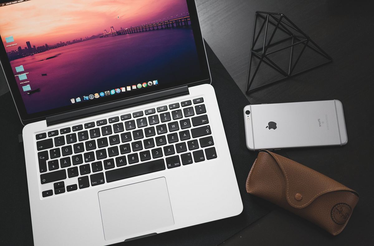 MacBook Pro beside space iPhone 6 on black wooden surface