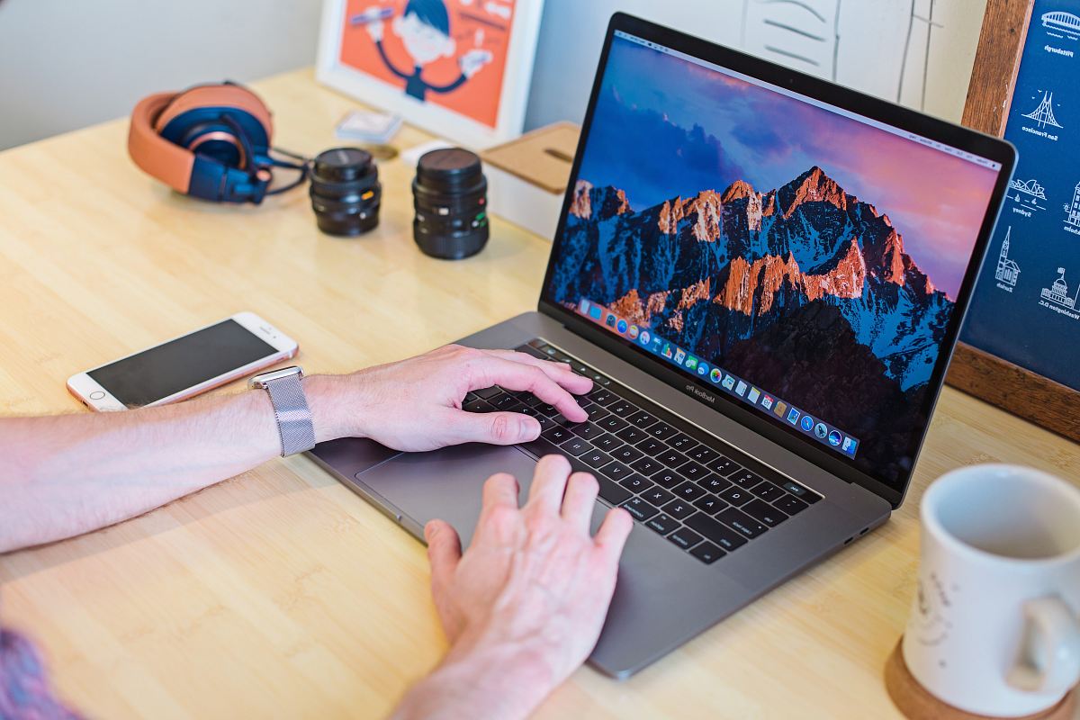 MacBook Pro turned on beside white ceramic mug