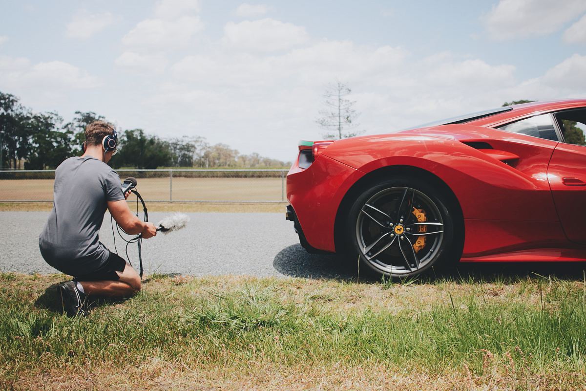 man behind car holding microphone measuring sound