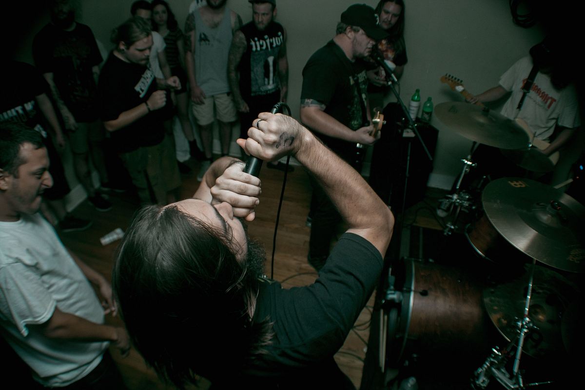 man holding black corded microphone near man wearing white crew-neck t-shirt