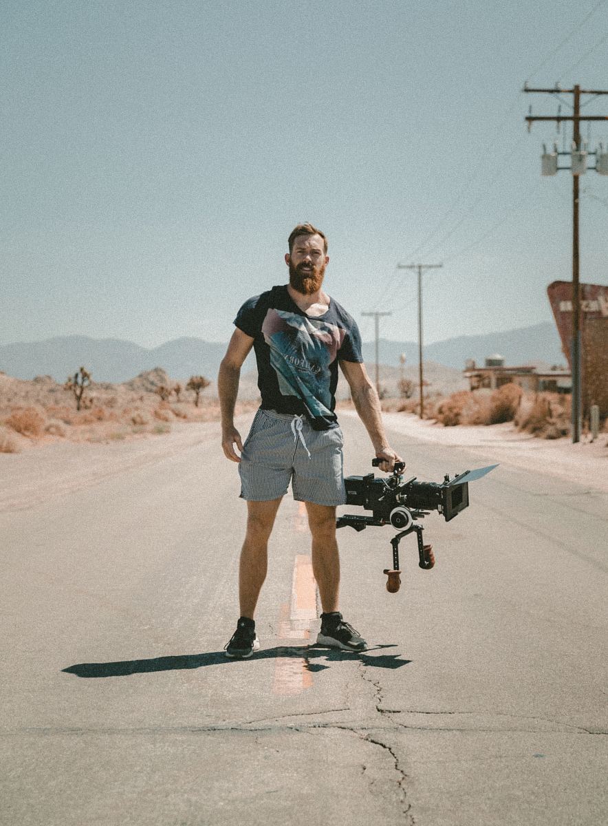 man holding camera standing on road during daytime