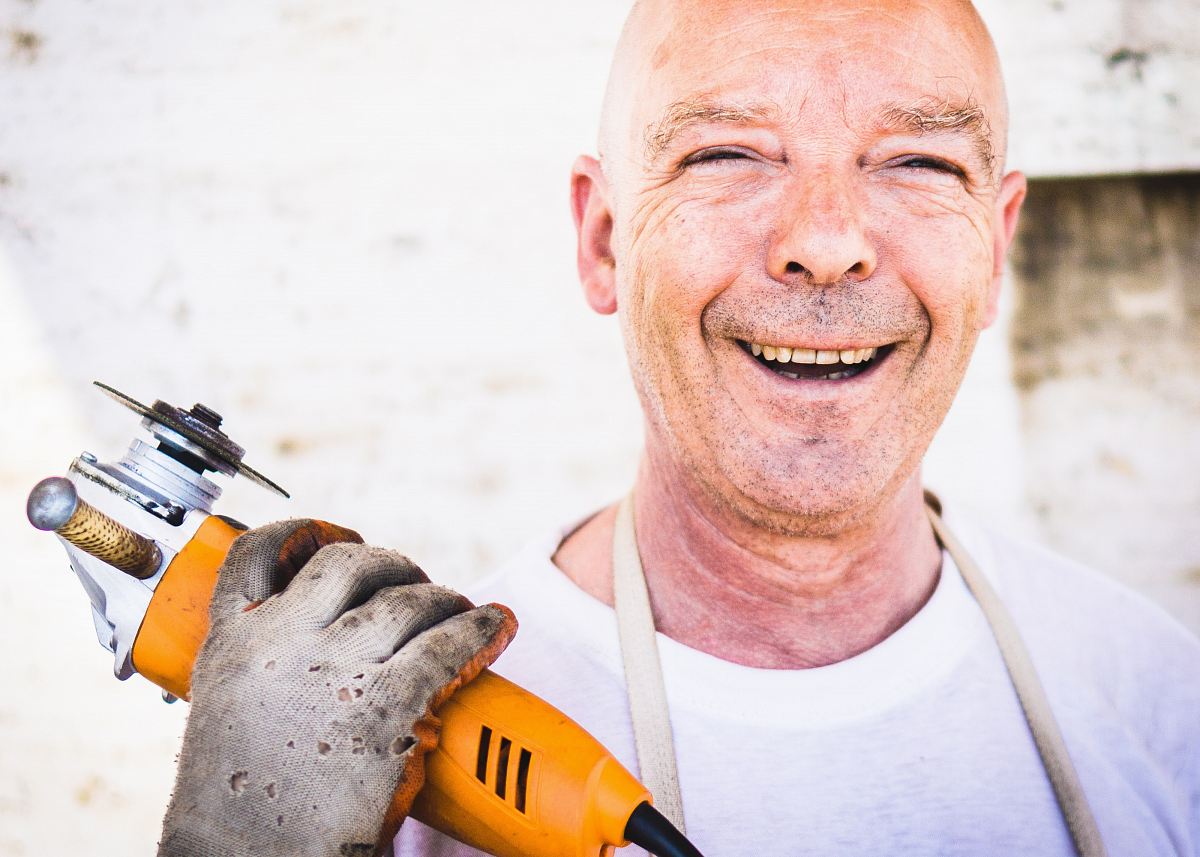 man holding orange angle grinder