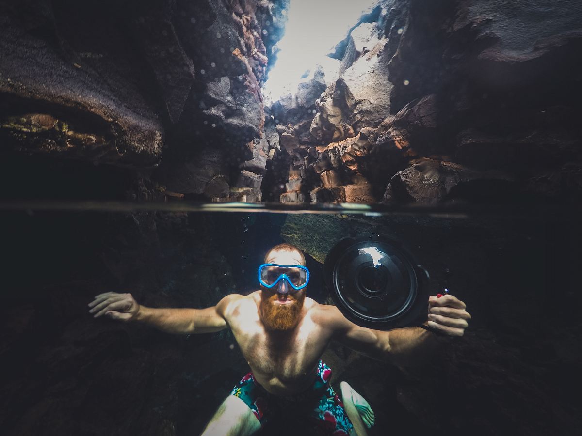 man in body of water between cliffs during daytime