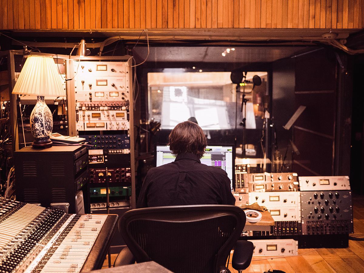 man in front of studio mixer and receiver