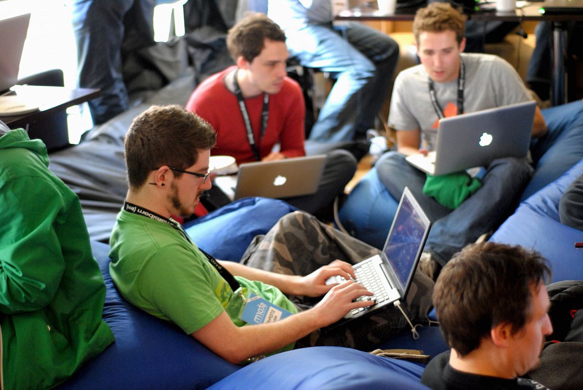 man sitting on blue bean bag usinglaptop