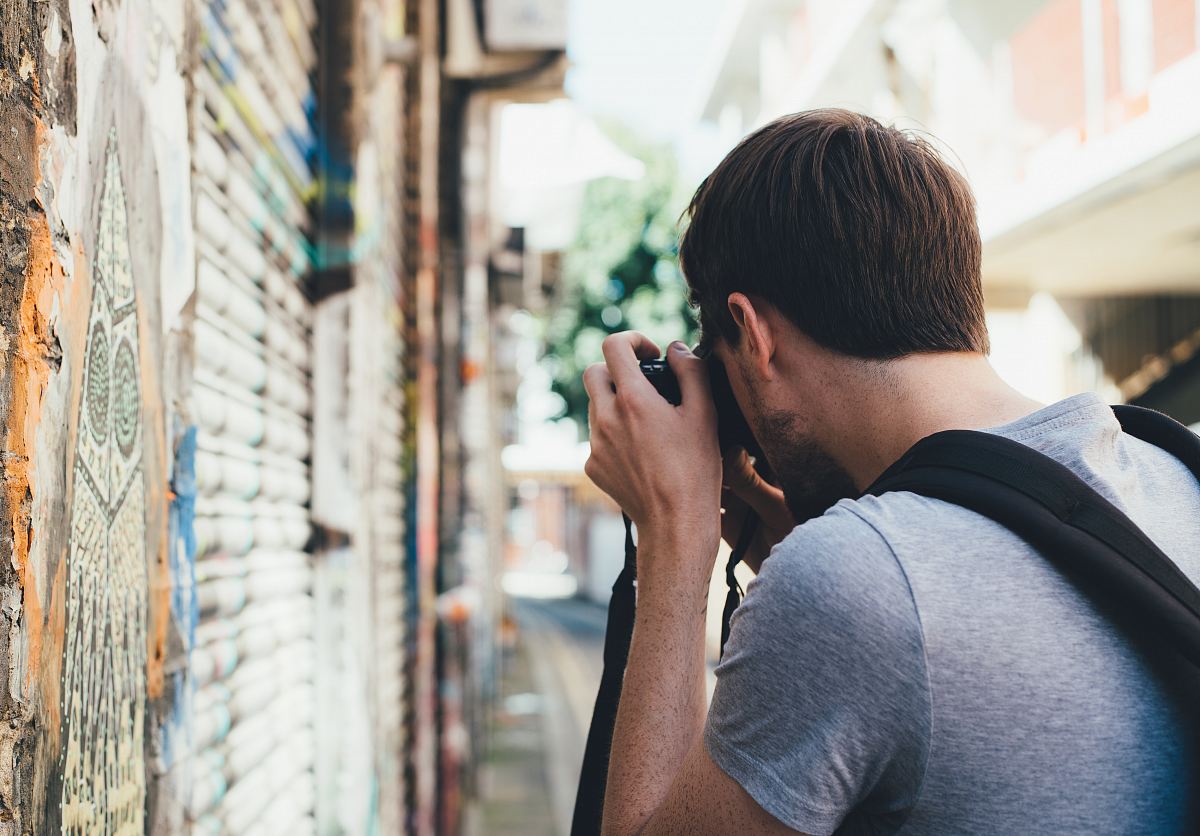 man taking a photo of wall painting during daytime