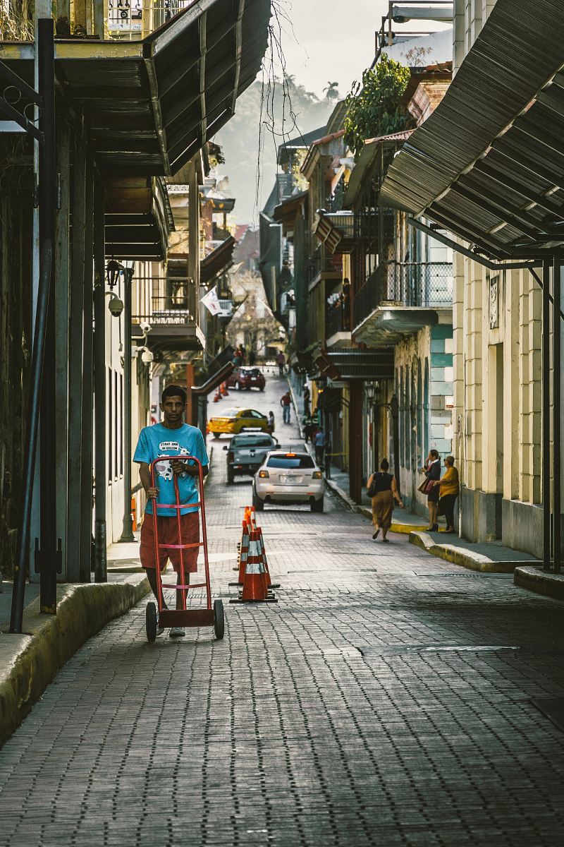 man wearing blue crew-neck shirt pushing handtruck