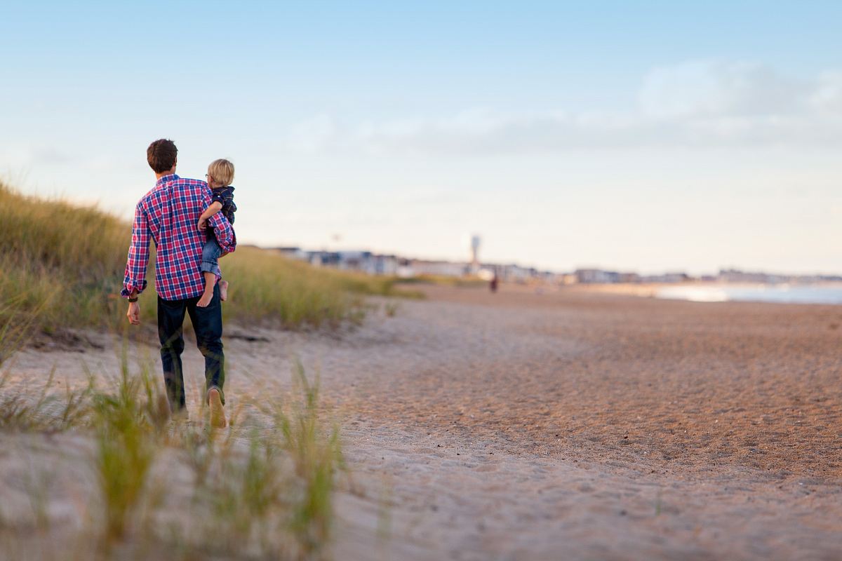 person carrying child while walking in front of oceon