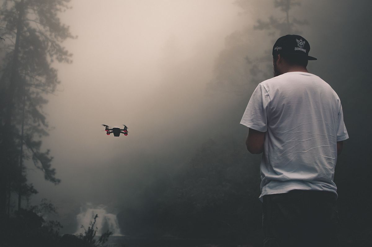 person facing drone near tree during daytime
