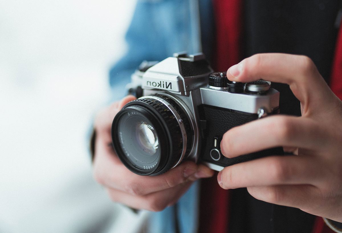 person holding black and gray Nikon DSLR camera